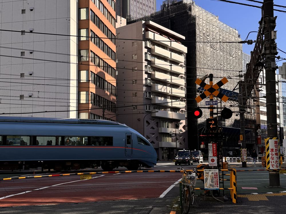 Tog ved Shinjuku Station Odakyu-tog krydser skinnerne ved en jernbaneoverskæring nær Shinjuku Station